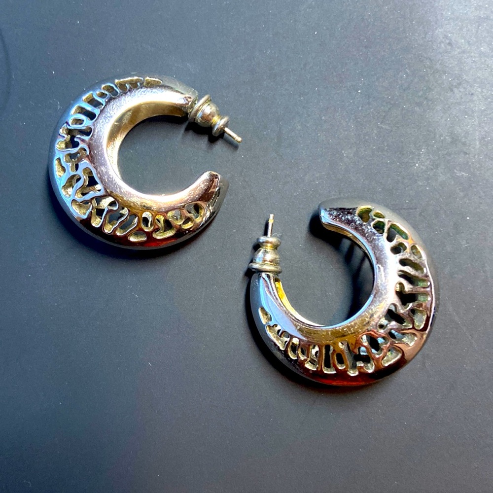Silver coloured metal pierced earrings with cutout design.